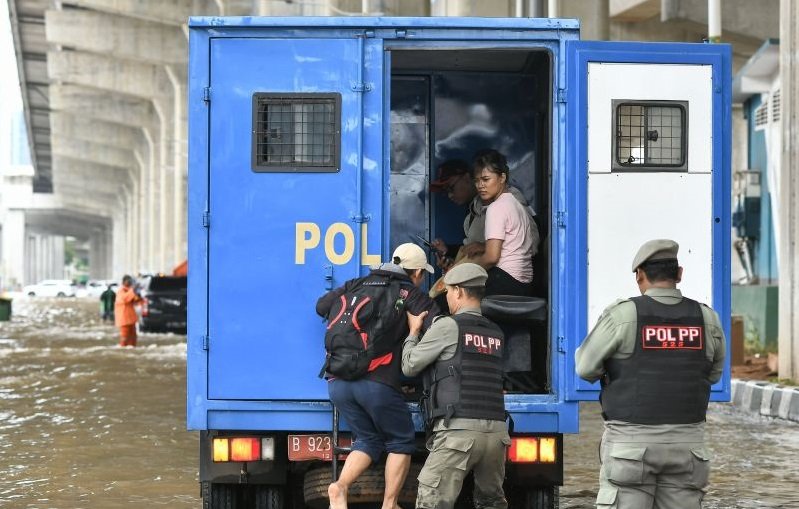 Petugas Satpol PP membantu pekerja untuk melintasi genangan air menggunakan truk di Jalan Boulevard Barat Raya, Kelapa Gading, Jakarta Utara, Rabu (29/1/2025). Foto: ANTARA 