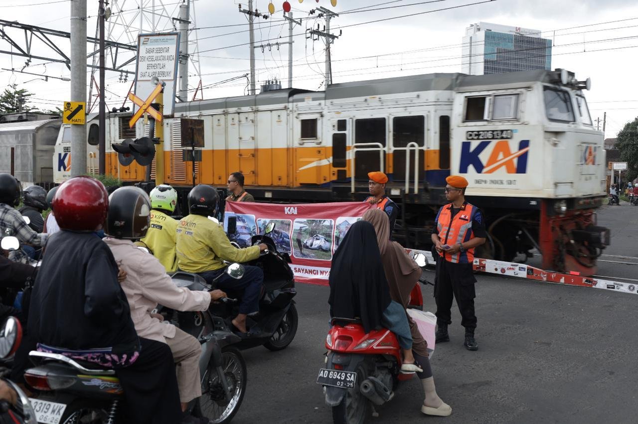 Petugas KAI Daop 6 Yogyakarta menggelar sosialisasi keselamatan di perlintasan sebidang sambil menahan laju kendaraan saat kereta api melintas, Selasa (30/4).